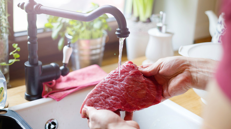 Rinsing steak under faucet