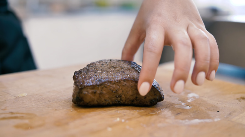 Poking a steak with finger