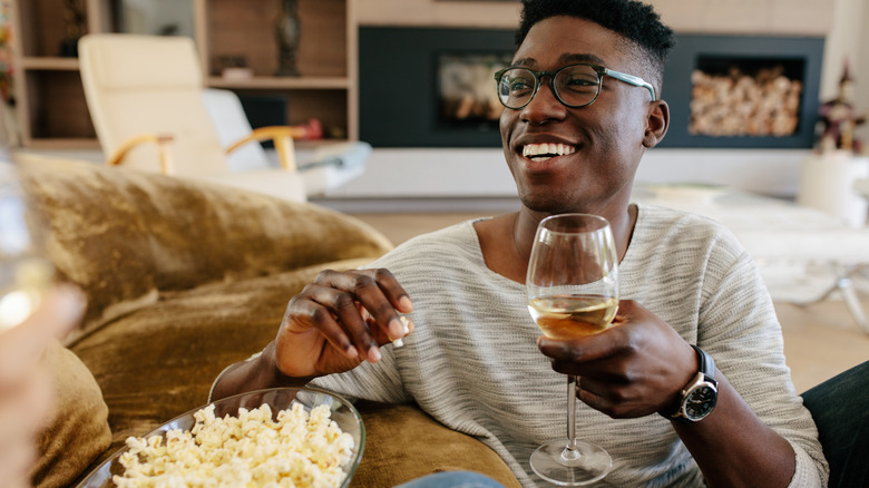 person enjoying glass of wine with popcorn