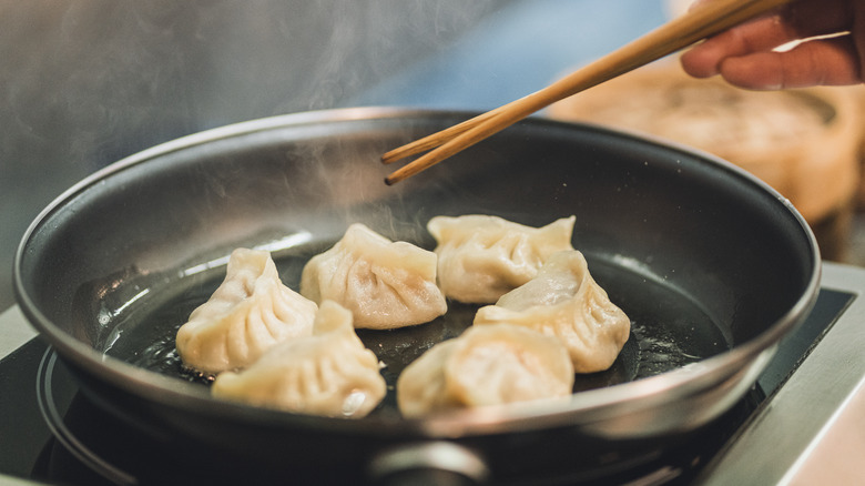 Person frying dumplings in pan