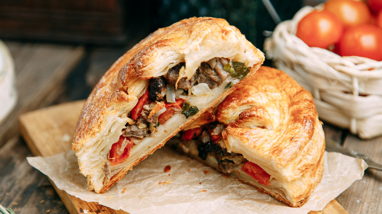 meat pies cut in half on wooden board