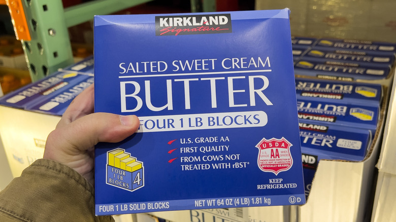 Shopper holding Kirkland Signature salted sweet cream butter at Costco