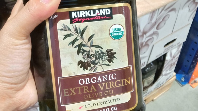 Hand holding bottle of Costco olive oil