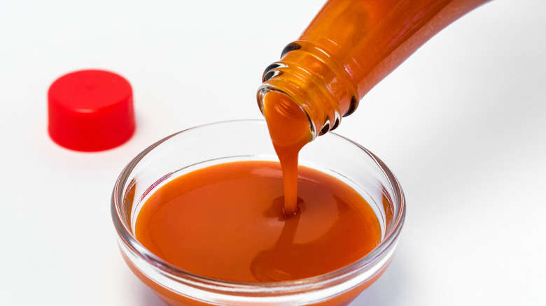 pouring hot sauce in bowl