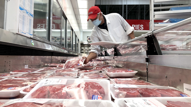 Butcher stocking Costco meat fridge