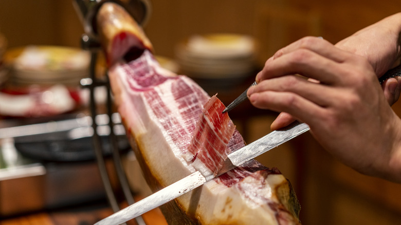 Person cutting serrano ham