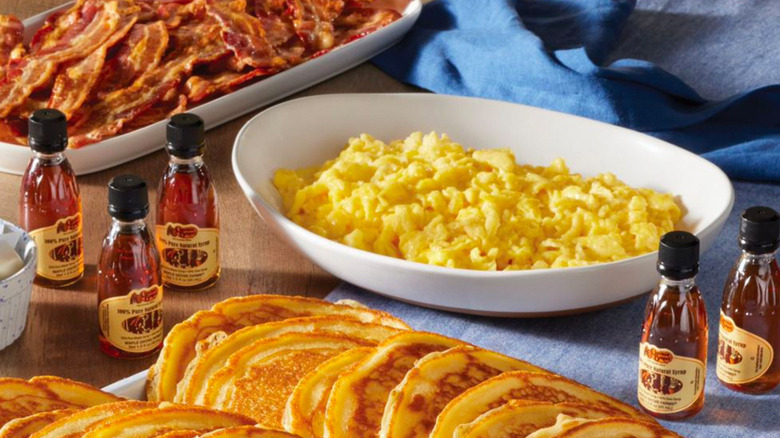 Serving bowl of scrambled eggs with mini bottles of Cracker Barrel syrup