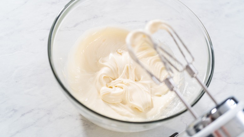 Electric hand mixer on cream cheese