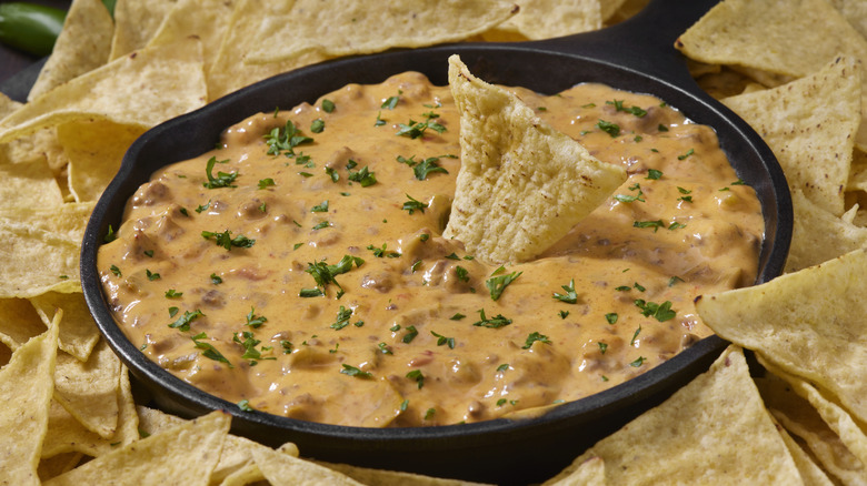 Cast iron pan of chili cheese dip surrounded by tortilla chips