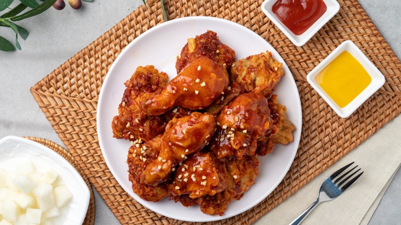 korean fried chicken with two dipping sauces on a bamboo placemat