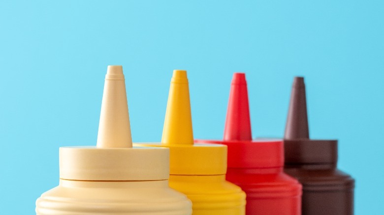 row of unmarked condiment bottles in white, yellow, red, and brown