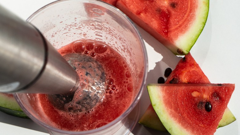 cup of watermelon juice with hand blender