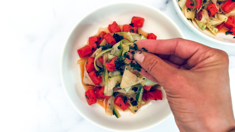 hand sprinkling cilantro onto salad