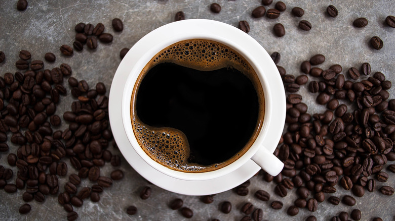 Top-down view of a cup of coffee with coffee beans