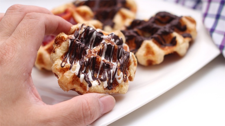 Hand holding waffle bite with chocolate
