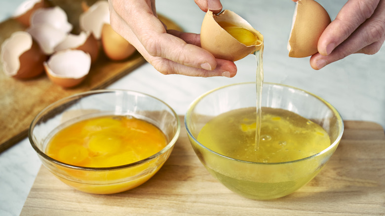 hand separating eggs and yolks into bowls