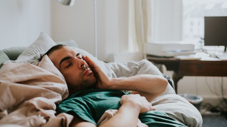 Man in bed grasping head