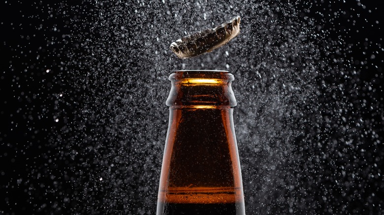 Bottle cap flies off the mouth of brown bottle