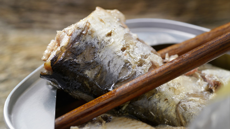 Using chopsticks to take sardines out of can