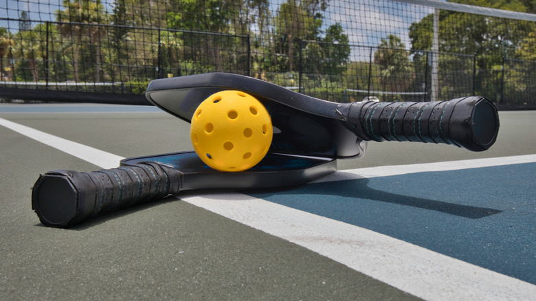 Yellow pickleball on court with rackets