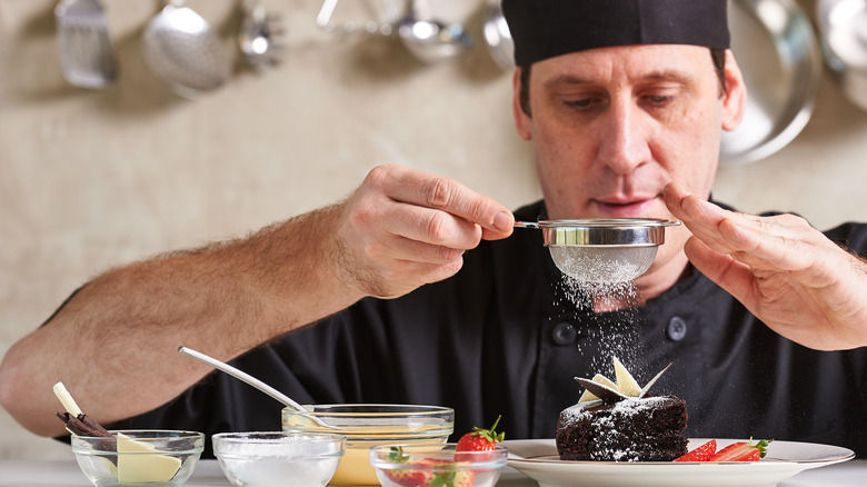 chef shaking powdered sugar over baked goods