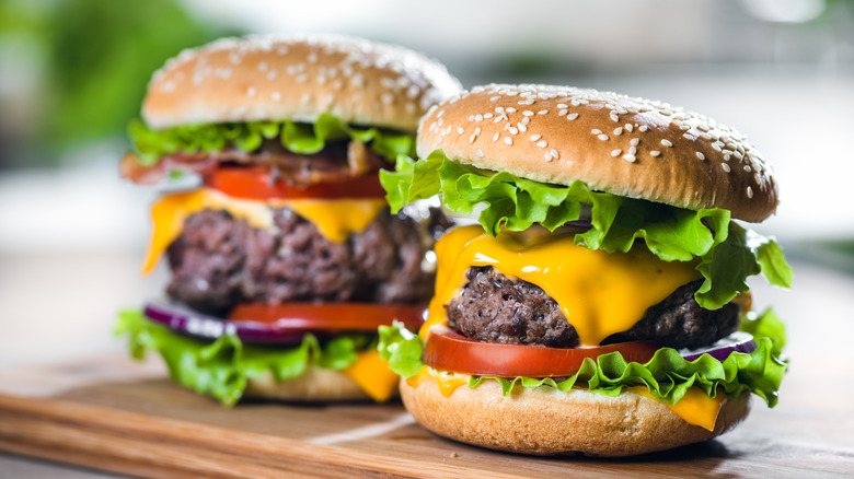 Two cheeseburgers on wooden platter