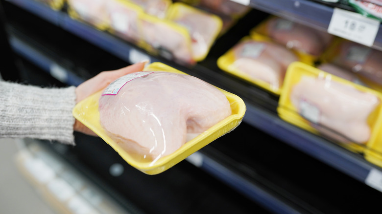 Someone purchasing chicken in plastic container