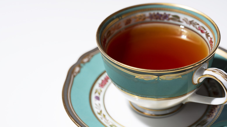 close up of tea in antique teal teacup and saucer