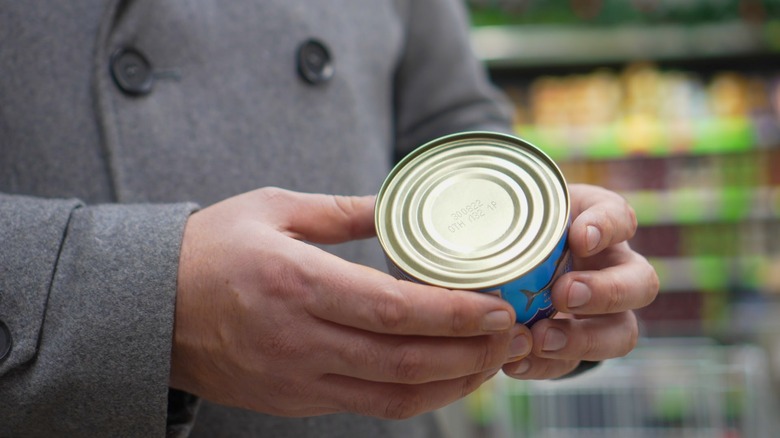 Person examining can of tuna