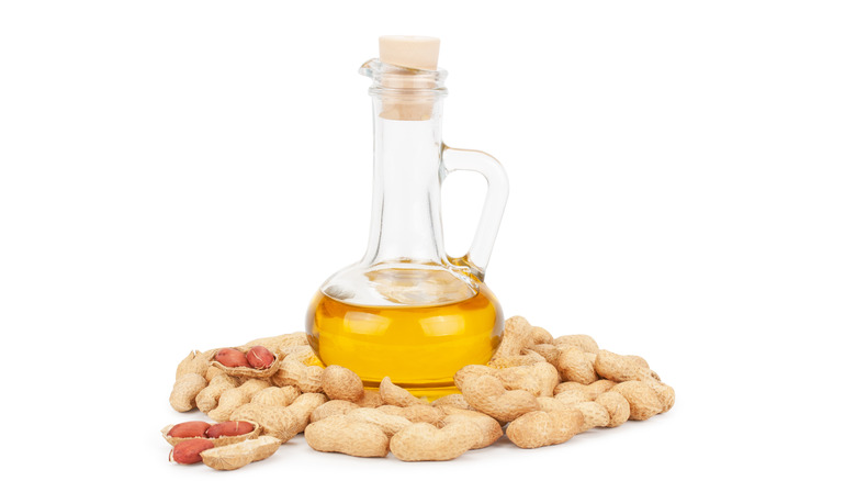 Peanut oil in bottle surrounded by peanuts