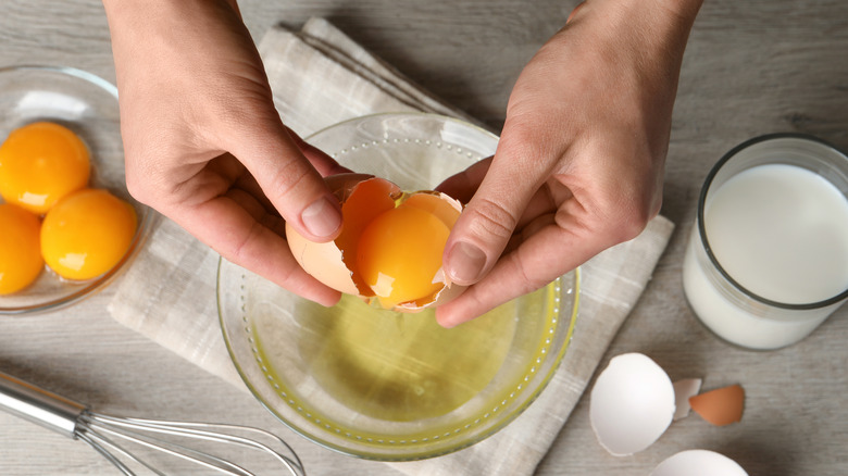 Hands cracking an egg into bowl