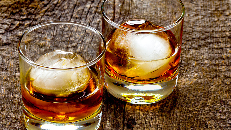 Two glasses of bourbon with large round ice cubes