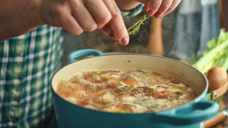 Seasoning a pot of soup with herbs