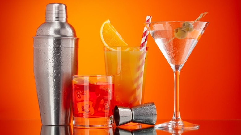 Drinks and shaker against orange background