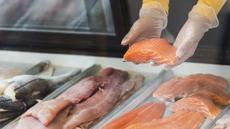 fishmonger picking up fresh salmon