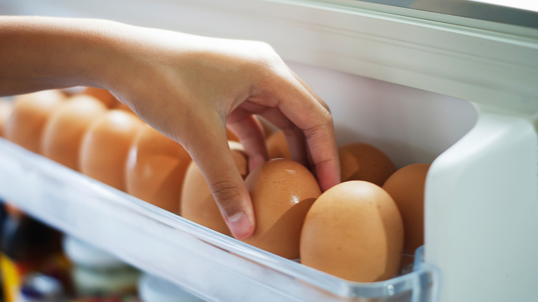 hand grabbing egg from refrigerator 