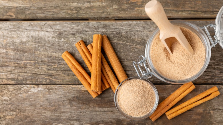 Cinnamon sugar in a jar next to cinnamon sticks