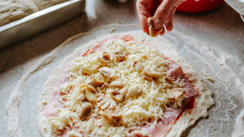 Person sprinkling cheese on pizza