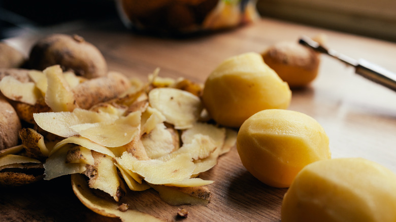 Potato skins beside peeled potatoes