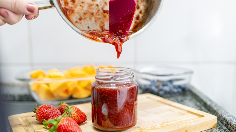 Homemade strawberry jam getting poured into jar