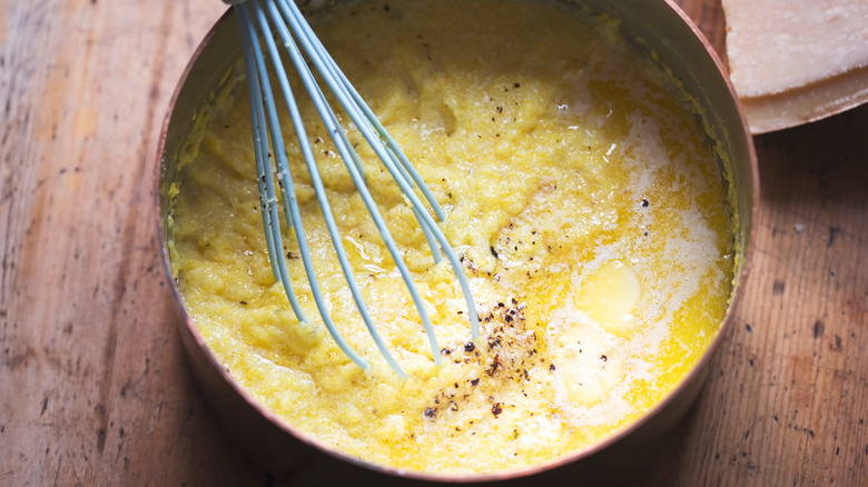 Pot of cooking polenta with whisk