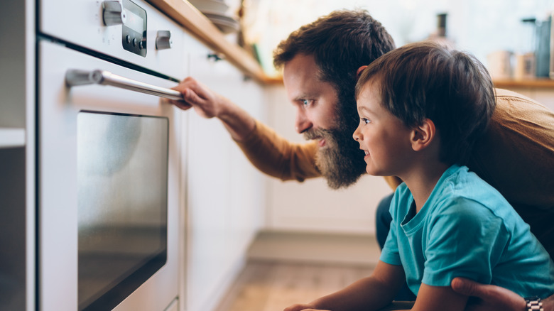 man and child using oven