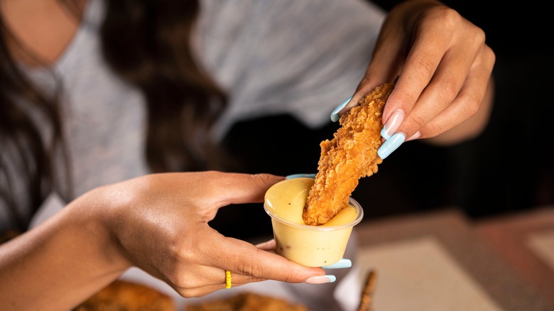 Woman dipping chicken in sauce