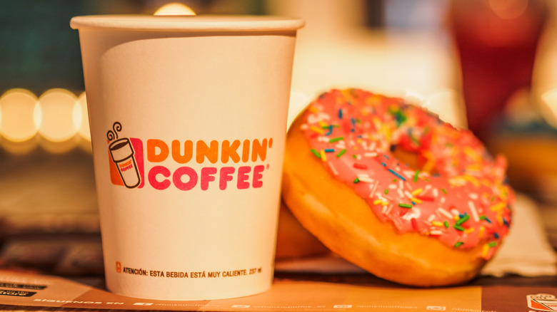 a dunkin coffee cup next to a dunkin donut