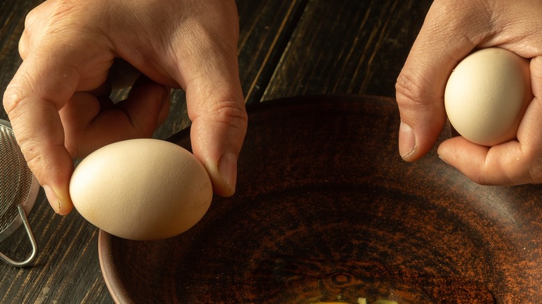 Eggs in hands over a bowl