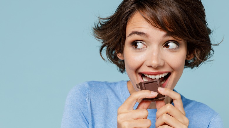 Woman bites a piece of chocolate