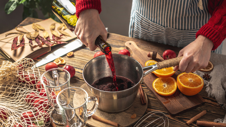 woman mixing up a batch of mulled wine with oranges in a pot