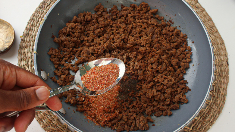 spoon of seasoning over plate of meat