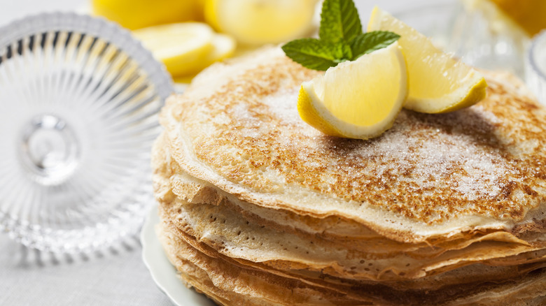 stack of pancakes dusted with sugar and lemon