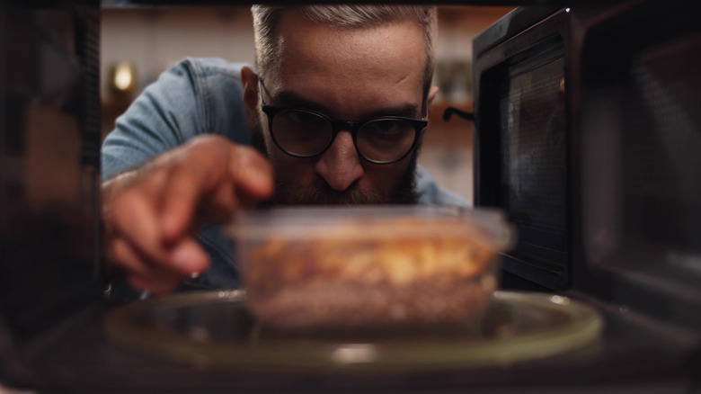 man reheating leftovers in microwave